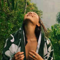 Woman in rainforest with towel draped around her
