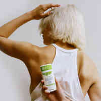 Woman with her back to the camera holding Schmidt's Bergamot and Lime deodorant behind her