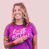 Woman holding her hand over her heart with a shirt that says love your breasts