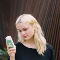 Woman holding schmidt's jasmine tea deodorant and looking down at it