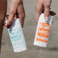 Two pairs of legs with two hands holding Schmidt's Waves deodorant next to their knees