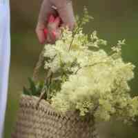 Woman holding flowers in basketweave bag