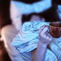 Woman in bed holding coffee cup