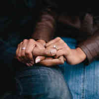 Two people holding hands sitting next to each other