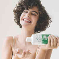 Woman pouring Jasmine tea body wash into hand