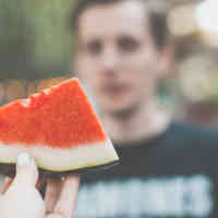 A hand holding a slice of watermelon.