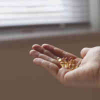 Een outstreatched hand die een handvol tabletten licht vasthoudt.