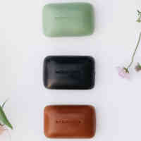 Schmidt's Rose+Vanilla, Charcoal+Magnesium, and Bergamot+Lime Bar Soaps on a white background next to pink and purple flowers