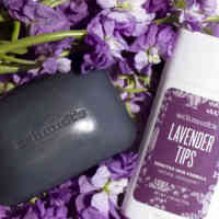 Schmidt's Lavender+Sage bar soap and Lavender Tips deodorant for sensitive skin on top of purple flowers and white background